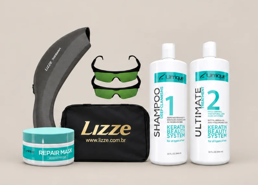 Lizzie Beauty System hair repair kit on a beige background, including a black hair dryer, black zippered pouch with gold Lizzie logo, green protective goggles, a white shampoo bottle, an ultimate repair mask bottle, and a repair mask jar.